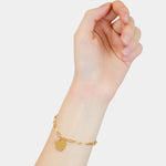 Eine Hand trägt das Liebeskind Berlin Armband - My Heart mit einem goldenen herzförmigen Anhänger auf weißem Hintergrund.