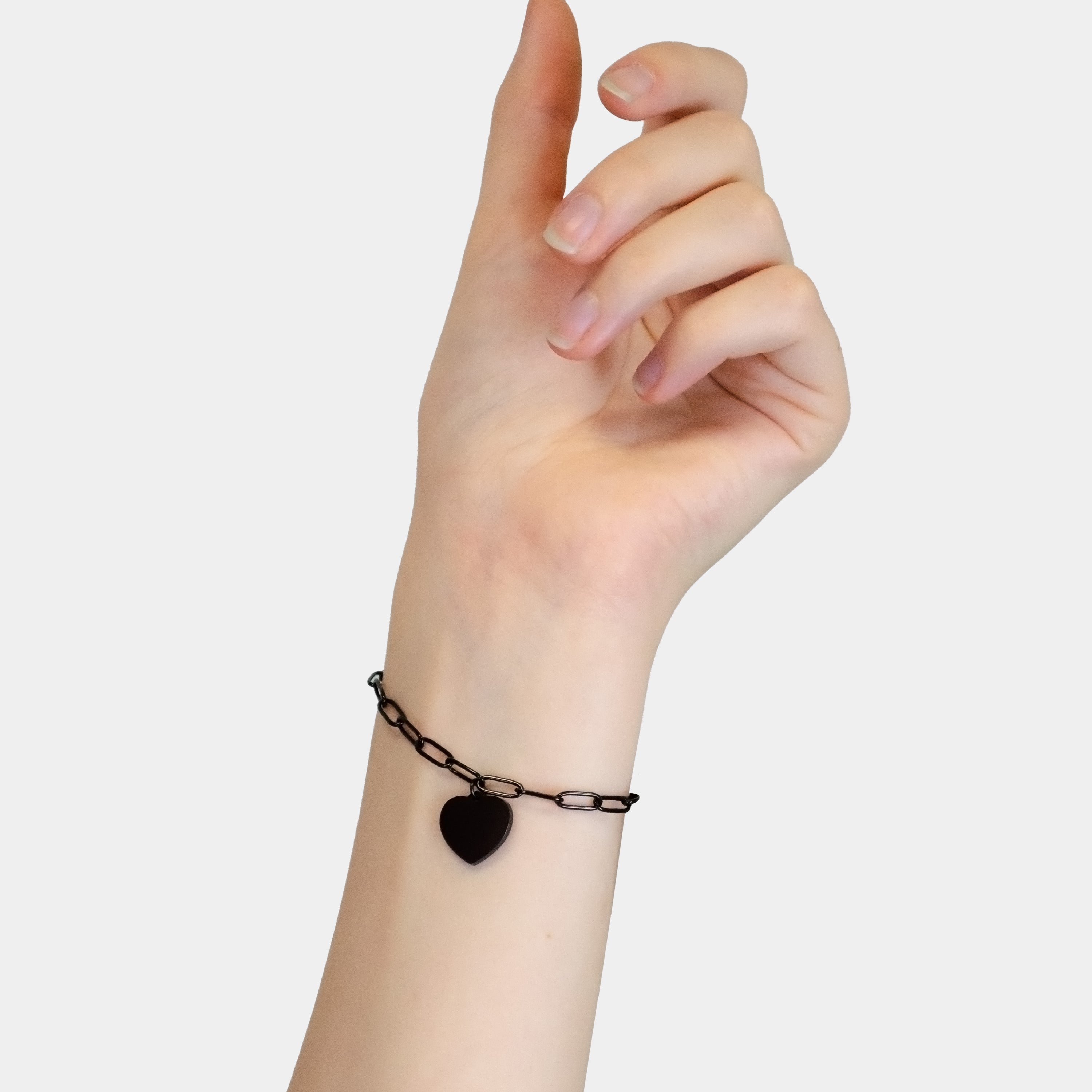 Eine Hand trägt das LIEBESKIND BERLIN Armband - My Heart von Liebeskind Berlin mit einem Herzanhänger vor einem schlichten hellen Hintergrund.