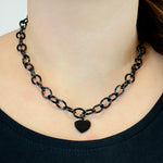 Die LIEBESKIND BERLIN Halskette - My Heart von Liebeskind Berlin aus Edelstahl mit Herzanhänger, stilvoll am Hals getragen und vor einem schwarzen Top präsentiert.