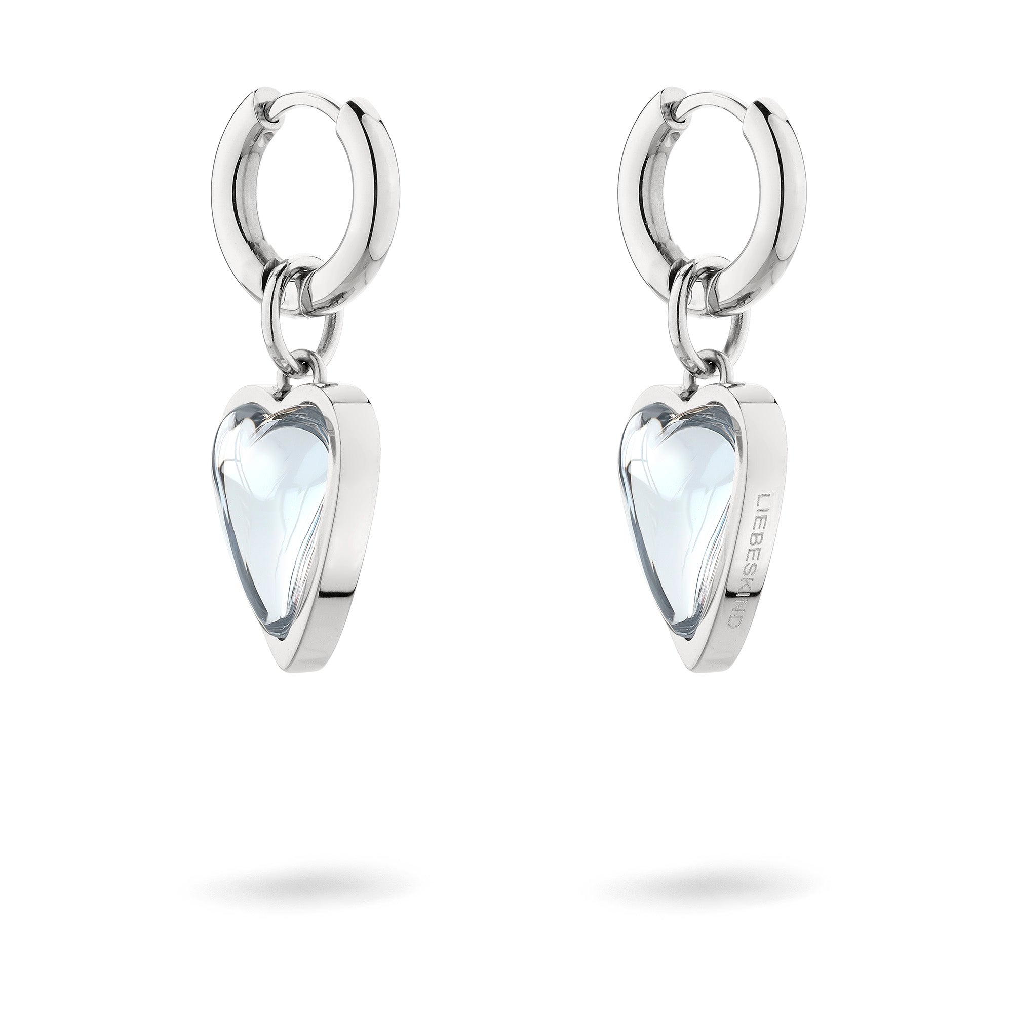 Die Ohrringe LIEBESKIND BERLIN Creole - Glass Heart von Liebeskind Berlin mit Herzanhängern aus klarem Glas auf weißem Grund sind eine elegante Accessoire-Wahl.