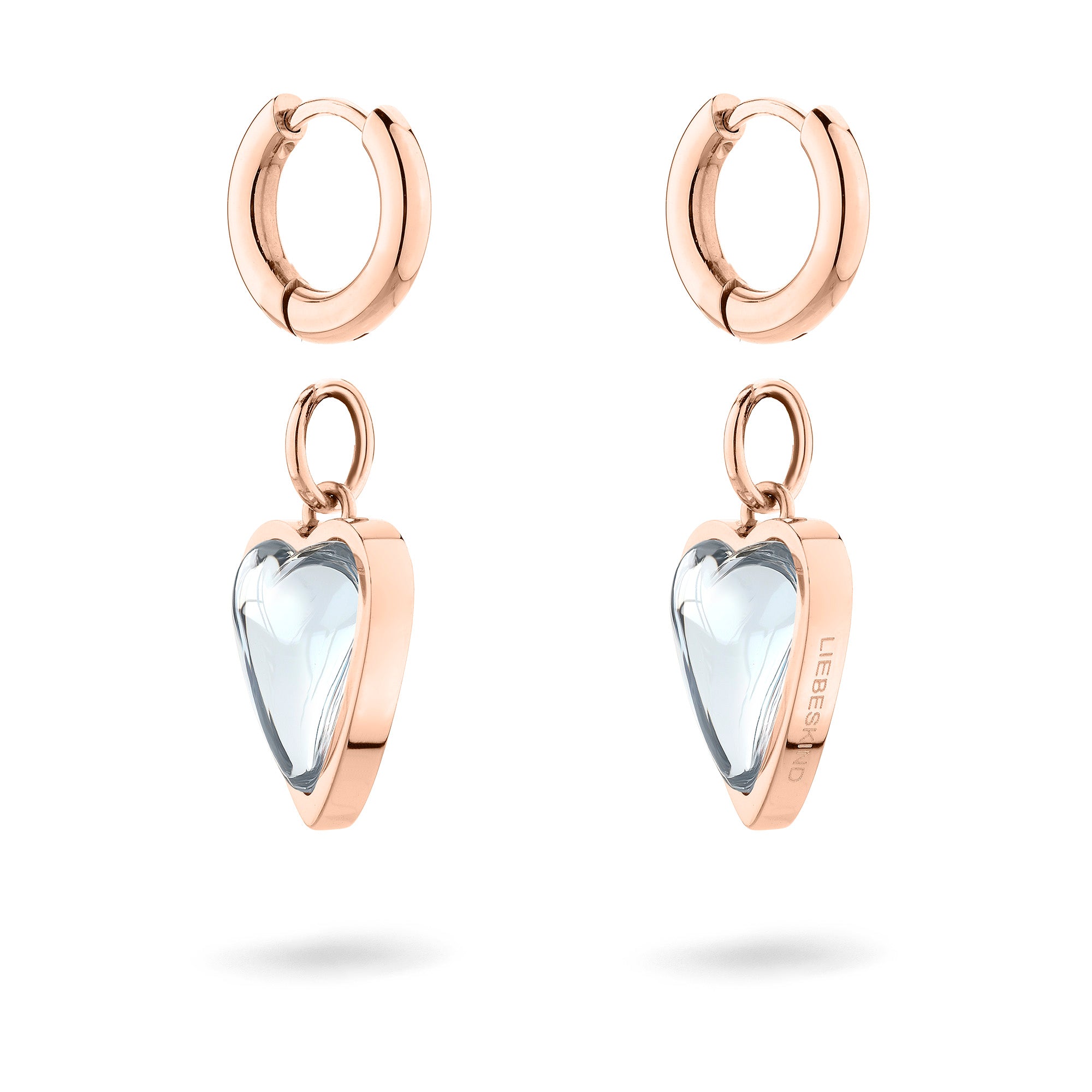 LIEBESKIND BERLIN Creole - Glasherz-Ohrringe von Liebeskind Berlin. Die Ohrringe aus Roségold mit baumelnden, klaren Herzanhängern werden elegant vor einem weißen Hintergrund in Szene gesetzt.