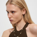 Eine Frau mit langen blonden Haaren trägt ein braunes Neckholder-Top und Liebeskind Berlin Ohrstecker - Glass Heart Ohrringe.