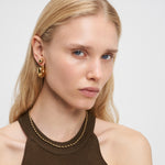 Frau mit langen blonden Haaren trägt goldene Ohrringe, ein braunes ärmelloses Top und die LIEBESKIND BERLIN Halskette - Steel Ball von Liebeskind Berlin.