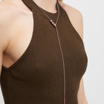 Eine Frau trägt ein ärmelloses, braunes, geripptes Oberteil und dazu die Liebeskind Berlin Halskette - Steel Ball, eine Kette mit kleinen Metallperlen für einen minimalistischen Look.