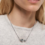 Eine Frau von den Schultern aufwärts trägt die Liebeskind Berlin Halskette - Steel Ball, mit geometrischen und kugelförmigen Anhängern, die das minimalistische Design unterstreichen.