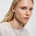 Eine Frau mit langen blonden Haaren und einem hellen Pullover trägt die LIEBESKIND BERLIN Halskette - Steel Ball von Liebeskind Berlin in einem minimalistischen Design und schaut leicht zur Seite.