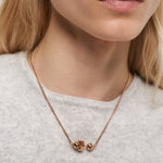 Eine Frau trägt die Liebeskind Berlin Halskette - Steel Ball über einem leichten Pullover und hebt das elegante, minimalistische Design mit geometrischen und kugelförmigen Anhängern hervor.