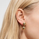 Nahaufnahme einer Frau, die den Liebeskind Berlin Ohrring - Steel Ball trägt, hervorgehoben durch ihr glattes blondes Haar.