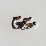 Zwei offene LIEBESKIND BERLIN Ring - Steel Ball von Liebeskind Berlin, einer goldfarben, einer silberfarben, zeigen modernes Design mit glänzenden Kugeln an den Enden - edle Accessoires vor weißem Hintergrund.