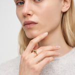 Eine blonde Frau, die einen Liebeskind Berlin Ring - Steel Ball und ein Nasenpiercing trägt, berührt ihr Gesicht und blickt in die Kamera, wobei sie modernes Designflair präsentiert.