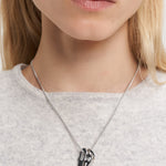 Eine Frau, die von den Schultern bis zu den Lippen gezeigt wird, trägt die Liebeskind Berlin Halskette - Organic Shapes mit einem abstrakten Anhänger.