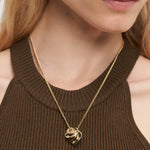 Eine Frau trägt die LIEBESKIND BERLIN Halskette - Organic Shapes von Liebeskind Berlin und ein ärmelloses braunes geripptes Oberteil, das einen subtilen Touch von Stil verleiht.