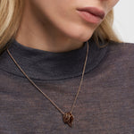 Eine Frau trägt eine Liebeskind Berlin Halskette - Organic Shapes über einem durchsichtigen, dunklen Rollkragenpullover.