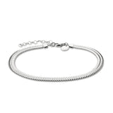 Die Liebeskind Berlin Fußkette - The Sleek ist eine silberne Fischgrätenkette mit verstellbarem Verschluss und einem kleinen runden Anhänger, der den charakteristischen Stil der Marke widerspiegelt. Abgebildet auf einem weißen Hintergrund.