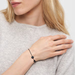 Eine blonde Frau trägt das Liebeskind Berlin Armband - You're my happy place mit einem hellgrauen Pullover, die Hand nahe ihrer Schulter.