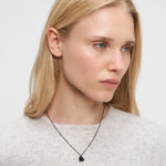 Eine Frau mit langen blonden Haaren trägt einen hellgrauen Pullover und eine Liebeskind Berlin Halskette - Broken Heart und schaut zur Seite.