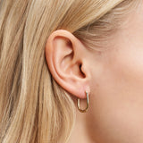 Nahaufnahme eines Frauenohrs mit glattem blondem Haar, das den Liebeskind Berlin Ohrring - Organic Shapes trägt - ein modernes Accessoire von Liebeskind Berlin mit goldenen, organisch geformten Ohrringen.