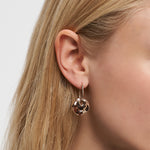 Nahaufnahme eines Frauenohrs, das den Liebeskind Berlin Ohrring - Organic Shapes trägt, einen goldenen Creolenring mit gedrehtem Design - ein modernes Accessoire von Liebeskind Berlin.