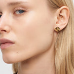 Nahaufnahme einer Frau mit blondem Haar, die den Liebeskind Berlin Ohrring - Organic Shapes trägt, gepaart mit mehreren kleinen Ohrpiercings - ein elegantes Accessoire, das mühelos Stil verleiht.