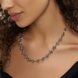 Eine Frau mit schwarzem Oberteil trägt die LIEBESKIND BERLIN Halskette - Spikes von Liebeskind Berlin, eine silberne Kette mit Stacheln, und hat ihr gewelltes Haar über eine Seite drapiert.