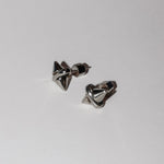 Ein Paar LIEBESKIND BERLIN Ohrstecker - Spikes von Liebeskind Berlin mit glänzendem, geometrischem Design, Silikonverschluss und dezentem Spikes-Muster wird auf einem schlichten weißen Hintergrund präsentiert.