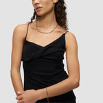 Eine Frau in einem schwarzen ärmellosen Top trägt die LIEBESKIND BERLIN Halskette - Urban Chic von Liebeskind Berlin und ein goldenes Armband und posiert vor einem schlichten Hintergrund.