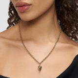 Eine Frau trägt eine Liebeskind Berlin Halskette - Metal Heart mit einem goldenen Herzanhänger und einem schwarzen schulterfreien Oberteil und betont damit eleganten Damen Schmuck.