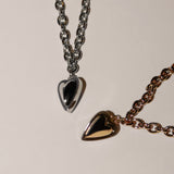 Zwei metallische Herzanhänger an Ketten, eine silberne und eine roségoldene, werden ausgestellt - und machen die LIEBESKIND BERLIN Halskette - Metal Heart von Liebeskind Berlin zu einem schicken Damen Schmuck-Highlight.