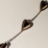 Goldfarbenes Armband mit glänzenden Herzanhängern, elegant in Szene gesetzt auf hellem Grund - perfekt zu kombinieren mit der LIEBESKIND BERLIN Halskette - Metal Heart von Liebeskind Berlin.