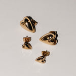 Vier goldene Ohrstecker in Herzform aus der Kollektion "Metal Heart" von Liebeskind Berlin sind auf einem schlichten weißen Hintergrund angeordnet - ein stilvolles Schmuckstück von Liebeskind Berlin Ohrstecker.