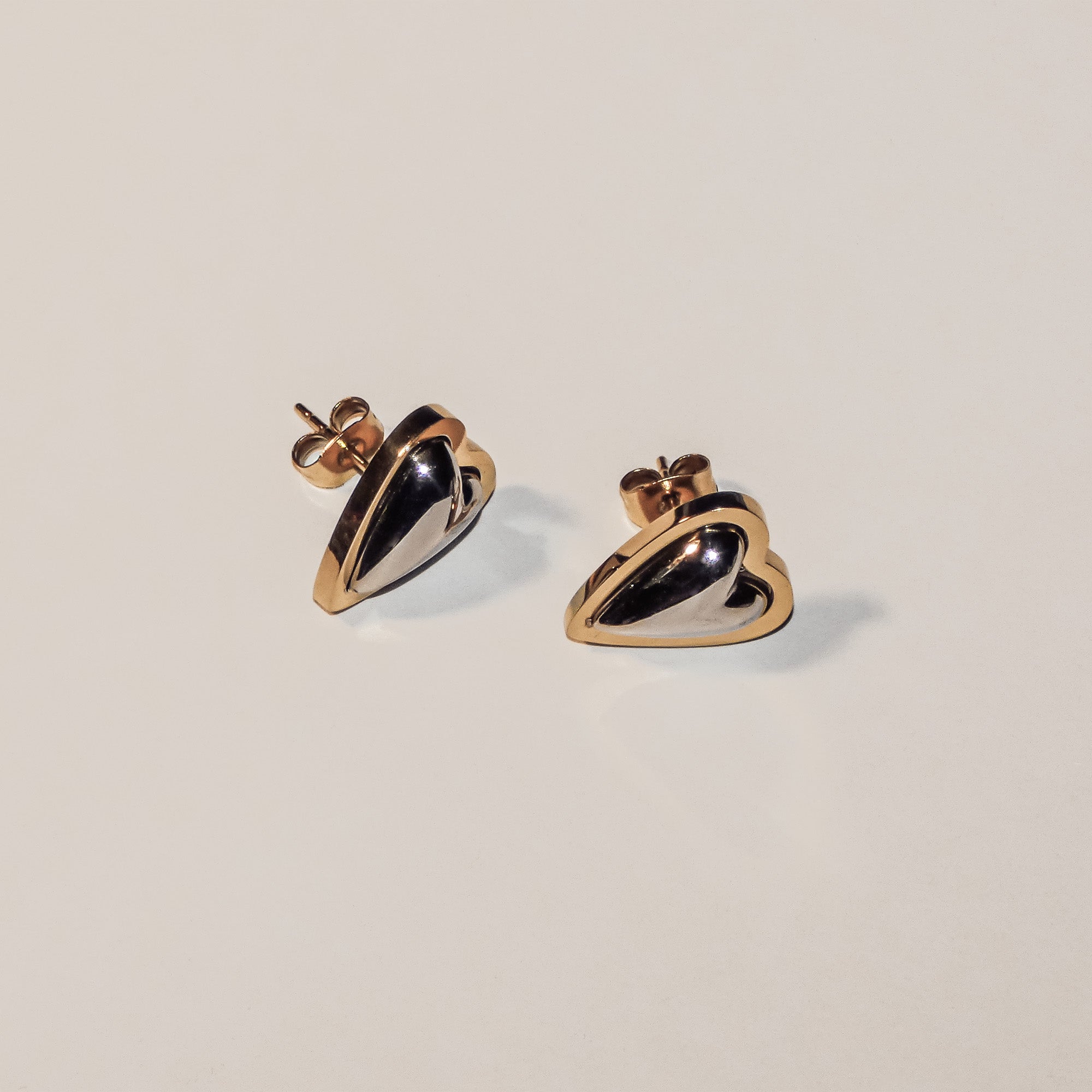 Bringen Sie Charme in Ihre Sammlung mit dem LIEBESKIND BERLIN Ohrstecker - Metal Heart von Liebeskind Berlin. Die herzförmigen Ohrstecker aus Gold und Silber in elegantem Design präsentieren sich auf einem schlichten, hellen Hintergrund.