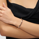 Eine Frau in einem schwarzen Oberteil trägt das Liebeskind Berlin Armband - Brick, ein Statement-Stück von Liebeskind Berlin mit Buchstabenperlen, auf denen "LIFE IS BEAUTIFUL" steht, an ihrem Handgelenk.