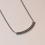 Die LIEBESKIND BERLIN Halskette - Twist von Liebeskind Berlin, mit einem spiralförmigen Anhänger an einer silbernen Schlangenkette, steht elegant auf einem schlichten weißen Hintergrund.