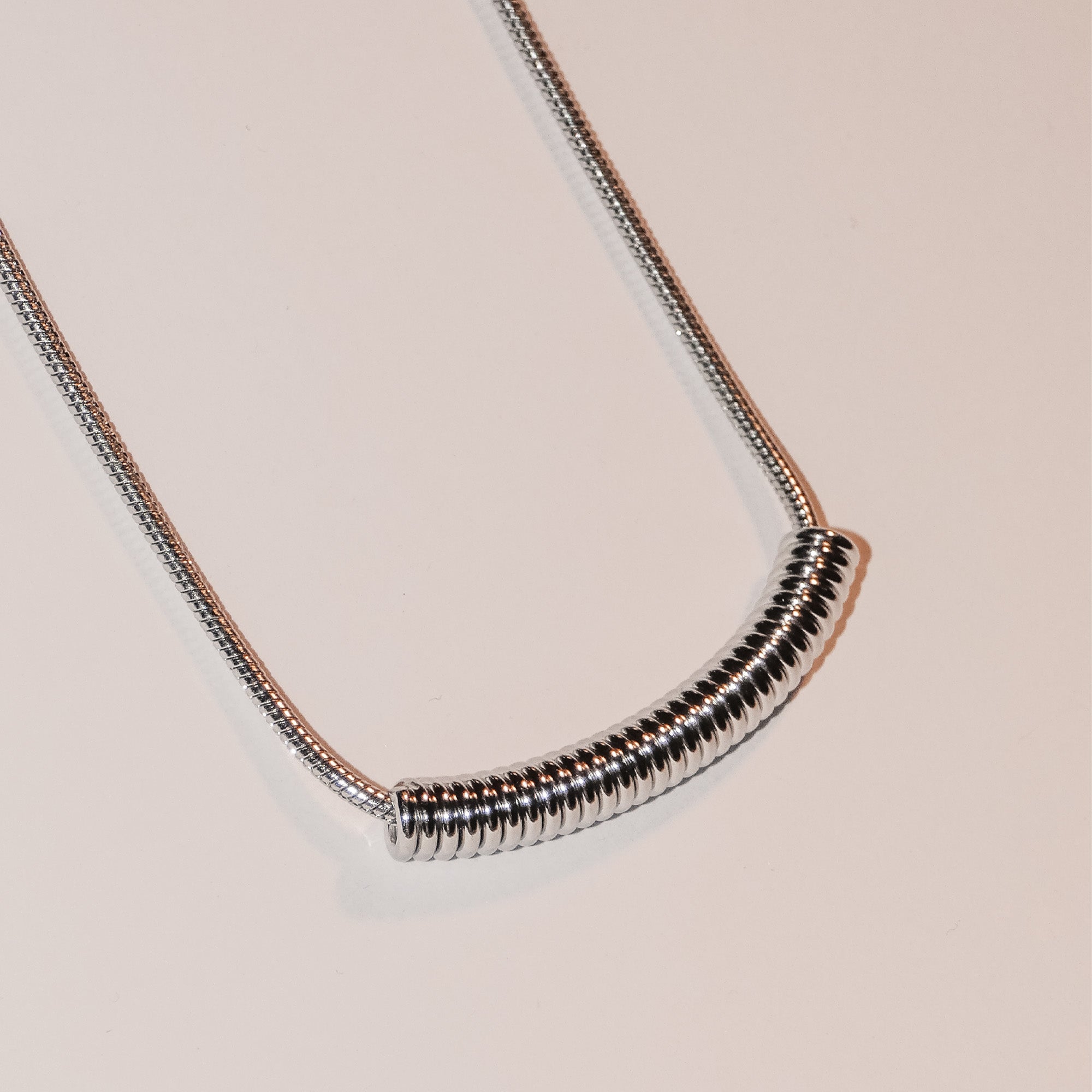 Die LIEBESKIND BERLIN Halskette - Twist von Liebeskind Berlin, mit einem spiralförmigen Anhänger an einer silbernen Schlangenkette, steht elegant auf einem schlichten weißen Hintergrund.
