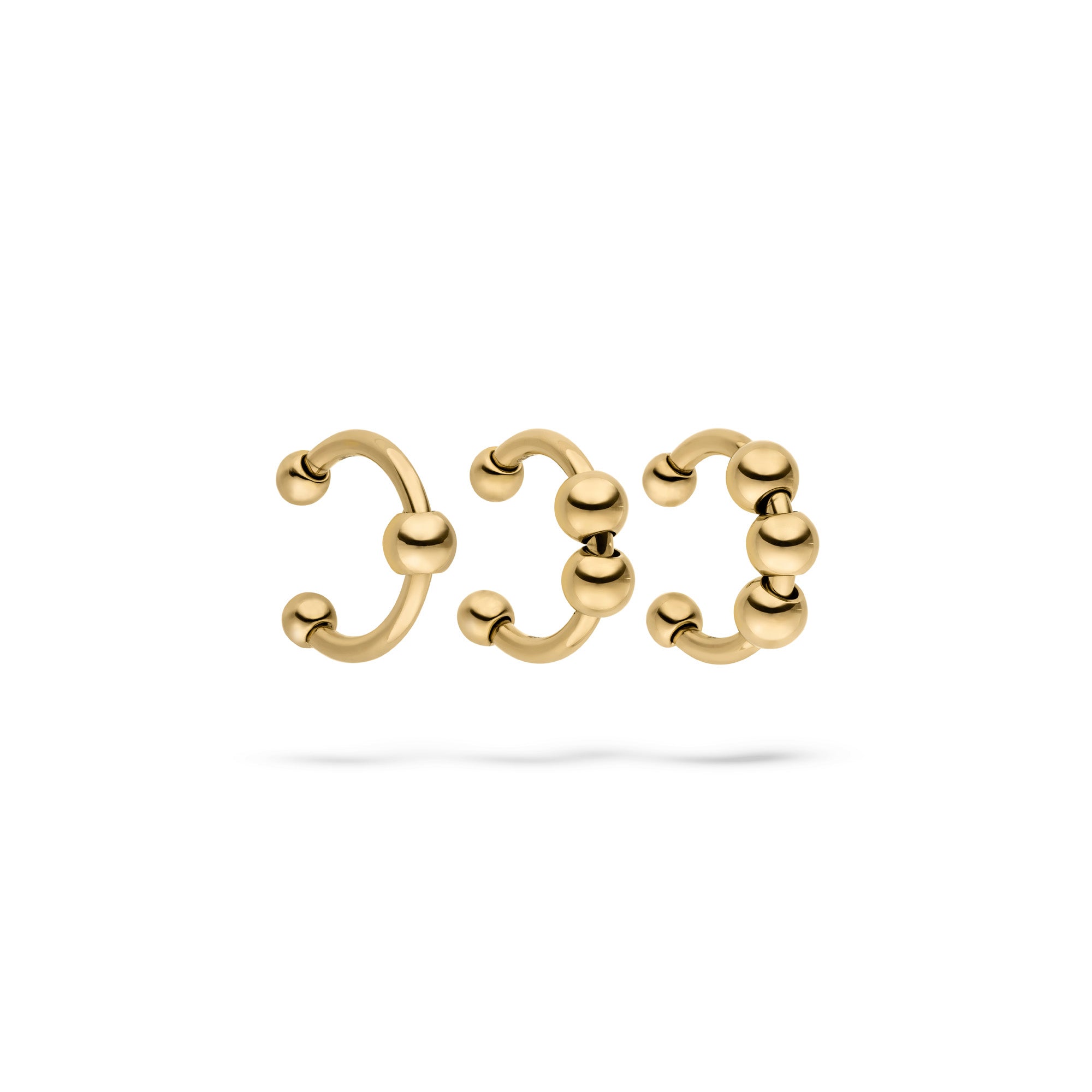 Das LIEBESKIND BERLIN Earcuff Set - Urban Chic von Liebeskind Berlin besteht aus drei goldfarbenen, offenen Ringen mit Kugelenden, die sich perfekt zum Kombinieren eignen und jedem Outfit einen modernen Touch verleihen. In einer Reihe auf weißem Hintergrund dargestellt.