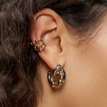 Nahaufnahme eines Frauenohrs mit dem LIEBESKIND BERLIN Urban Chic Earcuff Set von Liebeskind Berlin, gepaart mit goldenen und schwarzen Creolen für einen stilvollen, modernen Look.