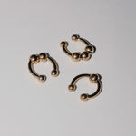 Drei goldene runde Ohrringe mit Kugelenden aus dem LIEBESKIND BERLIN Earcuff Set - Urban Chic von Liebeskind Berlin sind auf einer weißen Fläche platziert.
