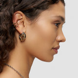 Eine Frau mit gewelltem Haar trägt mehrere goldene Ohrringe, darunter das LIEBESKIND BERLIN Earcuff Set - Urban Chic von Liebeskind Berlin, sowie eine Halskette; sie ist im Profil vor einem schlichten Hintergrund dargestellt.