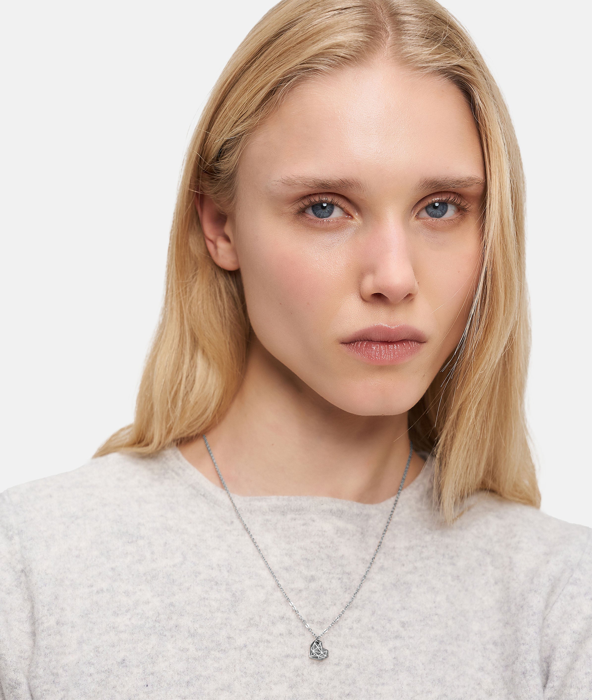 Model trägt die feine silberfarbene LIEBESKIND BERLIN Halskette mit geometrischem Herzanhänger aus dem Set Broken Heart Layering