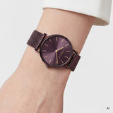 Ki generiertes Bild einer LIEBESKIND BERLIN Damenuhr mit violettem Edelstahl-Mesharmband, violettem Gehäuse und violettem Sunray-Zifferblatt mit goldfarbenen Zeigern und Indizes, getragen am Handgelenk.