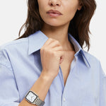 Frau in hellblauem Button-up-Hemd mit der LIEBESKIND BERLIN Armbanduhr - The Basic Staple von Liebeskind Berlin, Blick zur Seite.