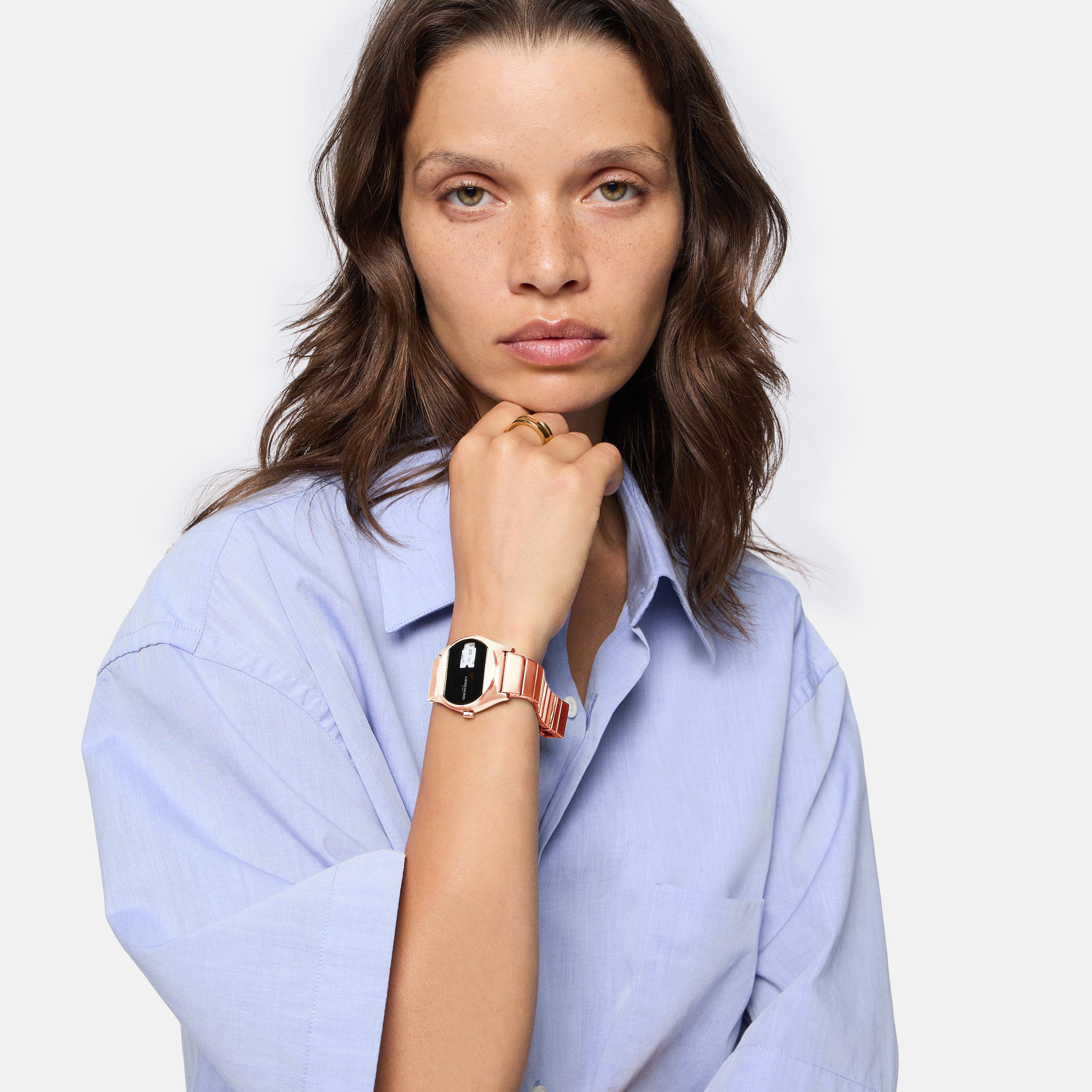 Frau in hellblauem Hemd mit Liebeskind Berlin Armbanduhr - Round Vinyl Vision, schaut mit neutralem Blick in die Kamera.