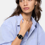 Eine Frau im hellblauen Hemd trägt die Liebeskind Berlin Armbanduhr - Round Vinyl Vision mit verspiegeltem Zifferblatt und blickt nachdenklich zur Seite.