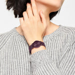 Person trägt einen grauen gerippten Pullover und die LIEBESKIND BERLIN Armbanduhr - Color Up von Liebeskind Berlin mit Edelstahl-Netzband in minimalistischem Design, die Hand berührt den Hals.