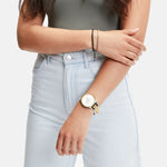 Frau trägt hellblaue Jeans, ein grünes Tank-Top und eine Liebeskind Berlin Armbanduhr - Classic x Trends im skandinavischen Design, sowie ein dünnes Armband, mit verschränkten Armen.