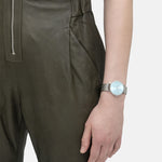 Eine Person im grünen Jumpsuit trägt die Liebeskind Berlin Armbanduhr - The Colorful Must-Have am linken Handgelenk.