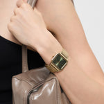 Eine Person, die die Liebeskind Berlin Armbanduhr - Vintage Classic mit Edelstahlmeshband trägt, hält eine taupefarbene Handtasche an ihrer Schulter.