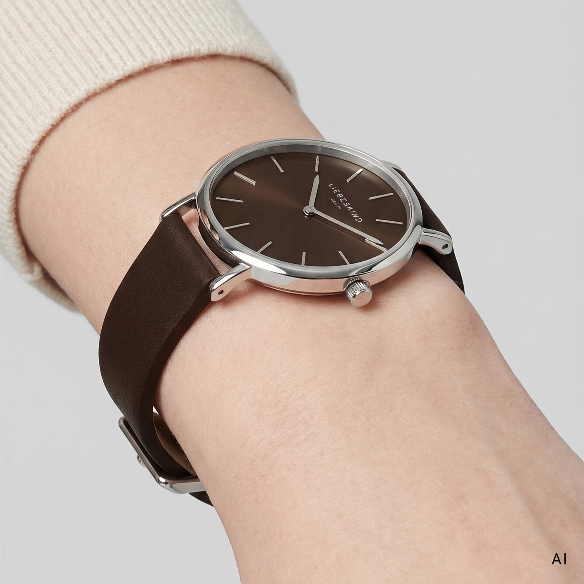 KI generierte Detailaufnahme einer LIEBESKIND BERLIN Damen Armbanduhr mit braunem Zifferblatt, silberfarbenem Edelstahlgehäuse und dunkelbraunem Lederarmband am Handgelenk getragen
