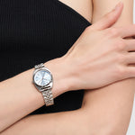 Eine Person trägt die LIEBESKIND BERLIN Armbanduhr - Das klassische Must-Have von Liebeskind Berlin mit Edelstahlarmband und einem schwarzen, ärmellosen Top, die Arme verschränkt über der Brust.