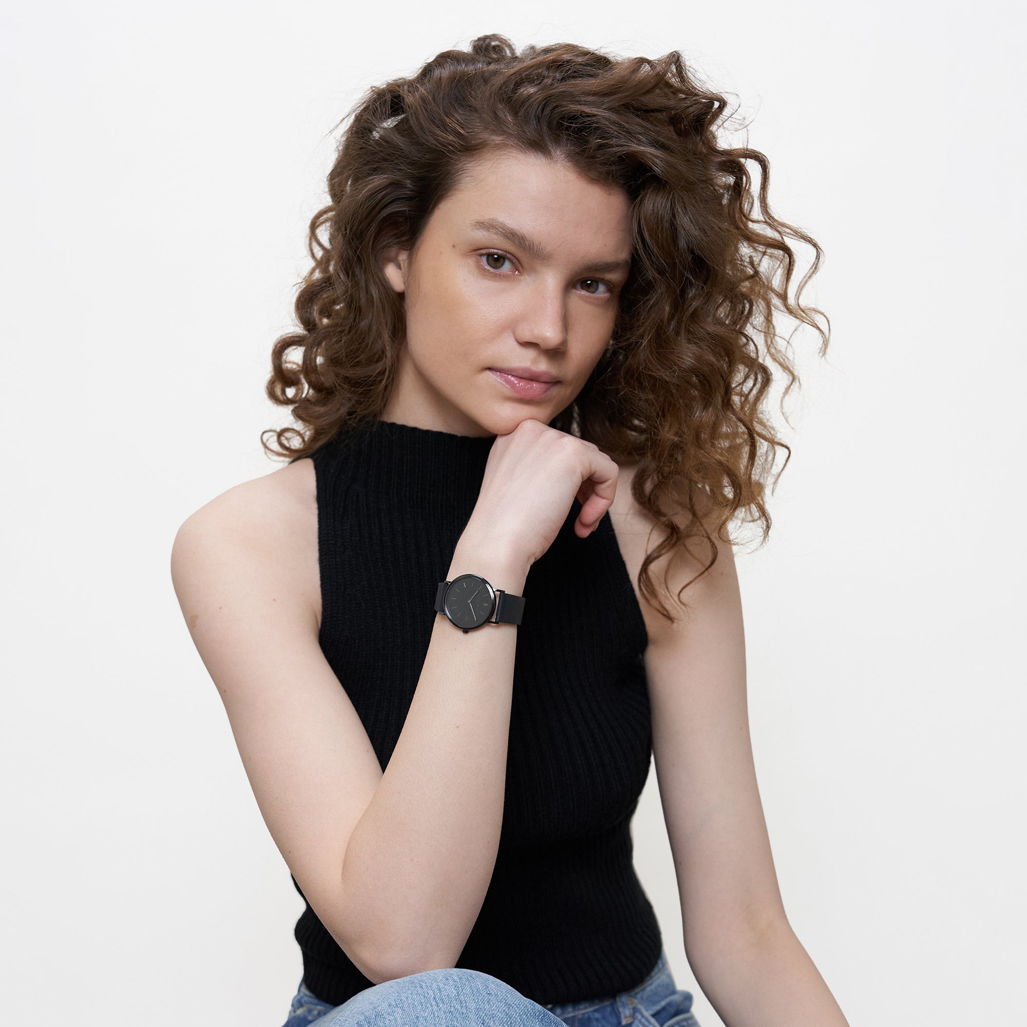 Schwarze LIEBESKIND BERLIN Damenarmbanduhr im All-Black-Look am Handgelenk eines Models mit schwarzem Top.